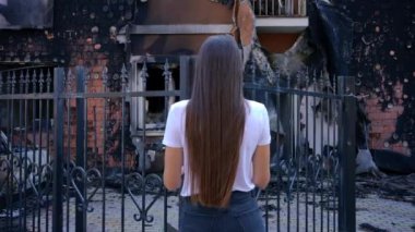 Arkadan bakan zayıf, genç bir kadın bombalanmış, yıkılmış bir eve bakıyor. Kiev banliyölerindeki kayıp evin önündeki Ukraynalı esmer kadın. Depresyon ve savaş konsepti