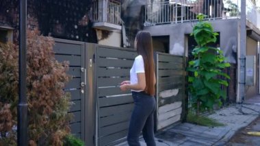 Ukraynalı umutsuz genç bir kadının portresi. Çitlere doğru yürüyordu. İç çekerek çaresizce iç çekiyordu. Şehir caddesinde bombalanmış bir eve bakan güzel bir kadın.