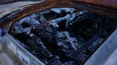 Ukrayna 'nın bombardıman bölgesinde iç kısımları yanmış. Dışarıdaki tahrip edilmiş araçta insan yok. Yan pencereden ateş ediliyor