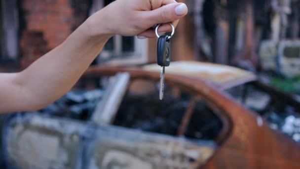 Großaufnahme Weibliche Hand Mit Autoschlüssel Und Zerstörtem Zerbombten Fahrzeug Hintergrund — Stockvideo