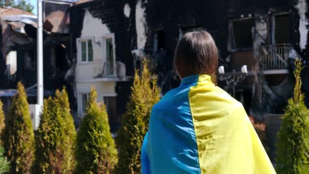 우크라이나 국기를 어깨에 도시의 거리에서 주위를 둘러보고 여자가 돌아본다 파괴된 — 비디오