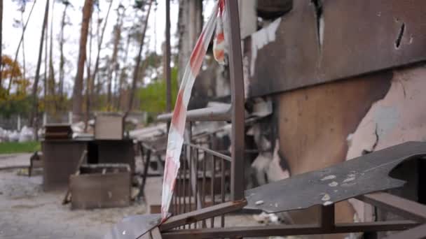 屋外の背景に壊れた損傷した家具と錆びた爆撃された家の残り物にぶら下がっている赤と白の注意テープ キエフウクライナの市民財産の遺跡を破壊した スローモーション — ストック動画