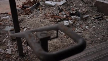 Bombalanmış evden arta kalanlarla çöplükten paslı metale odaklan. Açık havada yıkılmış bina parçaları. Yavaş çekim