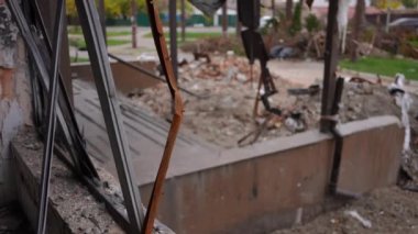 Ukrayna 'nın Kiev banliyösündeki savaş bölgesinde cam olmadan yanmış. Bulanık arabalar arka planda ağır çekimde yoldan geçiyor. Dışarıdaki çöplükle yıkılmış bir ev.