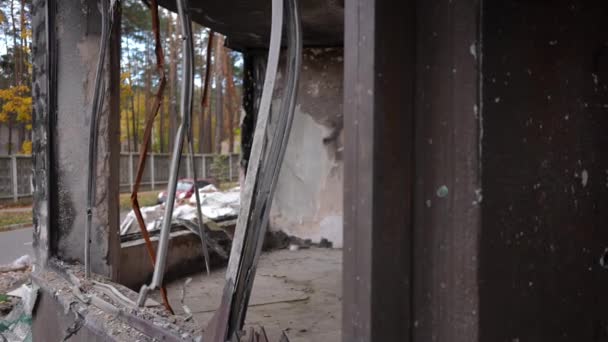 キエフウクライナの背景に郊外の道路を通過する赤い車と家の中で破壊された窓の破壊された金属構造を破壊しました 秋の日に屋外の荒廃した建物を破壊しました スローモーション — ストック動画