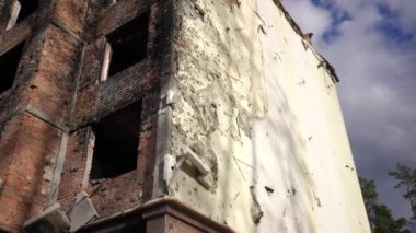 Bombalanmış çok katlı bina duvarı. Mavi gökyüzünün arka planında beyaz bulutlu. Canlı kamera Kyiv Ukrayna 'da yanmış bir arazide aşağı yukarı hareket ediyor. Savaş ve bombalama kavramı