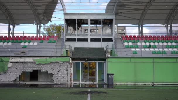 ワイドショットはウクライナのキエフのスポーツグラウンドで爆撃された観客席を損傷した 屋外に壊れた窓のあるフロントビューチェアとコメンテーターブース 戦争と空襲の結果 — ストック動画
