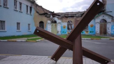 Arka planında bombalanan hasarlı bina olan Çek kirpileri. Ukrayna 'da açık havada tanksavar savunması. Rus-Ukrayna savaş konsepti