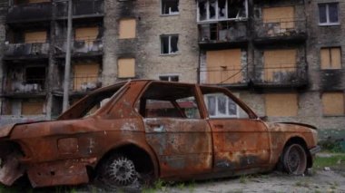 Yan görüş paslı, yanmış bir otomobil. Açık havada kül olmuş bir evde. Ukrayna 'nın mahvolmuş kentsel şehrinde bombalanmış bir araba. Yavaş çekim