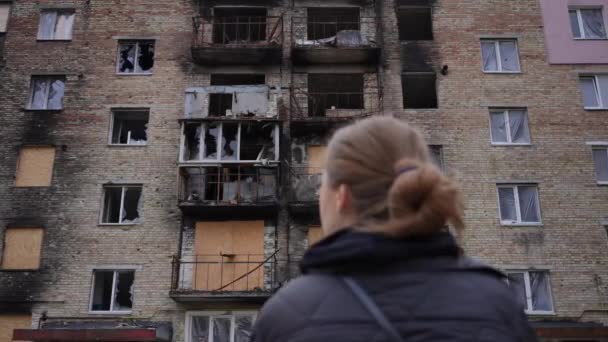 被毁的多层民房 前面有一个模糊的女人看着丢失的财产 乌克兰城市一座被炸毁的房屋被炸毁 无法辨认的乌克兰女士的后视镜 — 图库视频影像