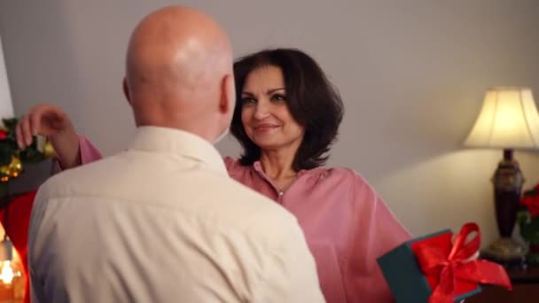 Uśmiechnięta Dorosła Żona Przytulająca Męża Dziękując Świąteczny Prezent Stojący Domu — Wideo stockowe