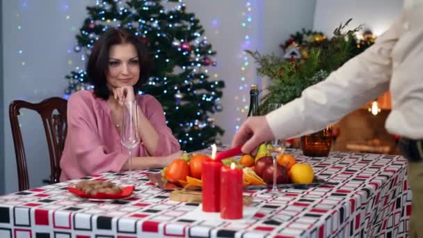 微笑的女人坐在圣诞餐桌旁 就像一个看不见的男人点着蜡烛 与浪漫的丈夫共度除夕之夜的快乐爱妻的画像 生活方式和假期 — 图库视频影像