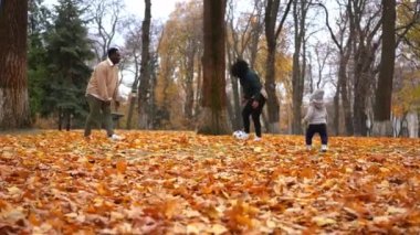 Afrika kökenli Amerikalı bir babanın portresi anne ve küçük oğlunun sarı çayır üzerinde düşen yapraklarla futbol oynamaları. Mutlu kaygısız erkek kadın ve çocuk sonbahar gününün tadını çıkarıyor.