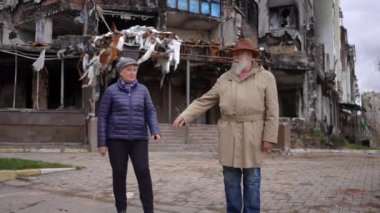 Mahvolmuş Ukrayna şehrinde durup ağır çekimde el ele tutuşan üzgün yaşlı adam ve kadına yakınlaşın. Çaresiz Kafkasyalı yaşlı çift bombalanmış evde.