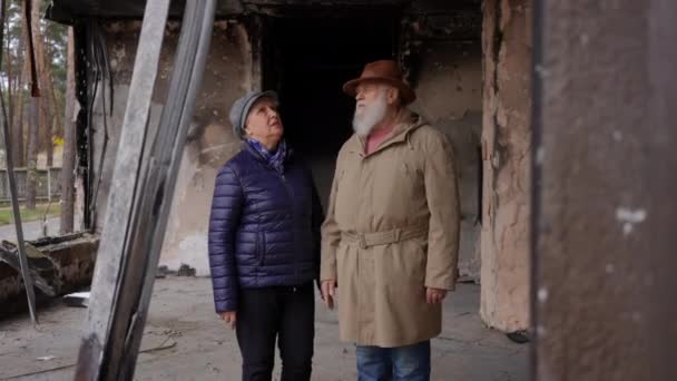 在被轰炸的乌克兰城市 悲伤的老年男女站在残破的房屋前聊天的画像 老两口在被毁的民宅里战争与绝望概念 — 图库视频影像