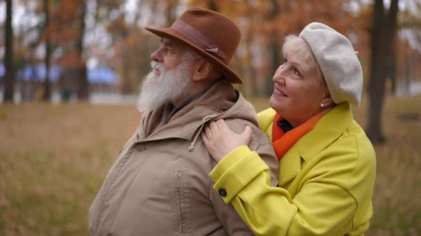 侧面看 快乐的老人把目光移开 而女人抱着肩膀站在后面 爱白种人的年长丈夫回头看妻子笑了 生活方式和爱情概念 — 图库视频影像