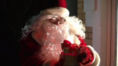 Noel Baba kostümü ve gözlük takmış heyecanlı beyaz adam Noel hediyesi kutusunu açıyor ve içinde ışık kapıdan ışığa dönüşüyor. Olumlu adam yeni yıl gecesi verandada dikilerek sürpriz yapıyor.