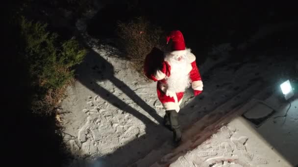 平安夜 拿着礼物袋的圣诞老人走到后院的门廊前环顾四周 身穿红色服装的白人男子在户外雪地上准备出其不意的画像 — 图库视频影像