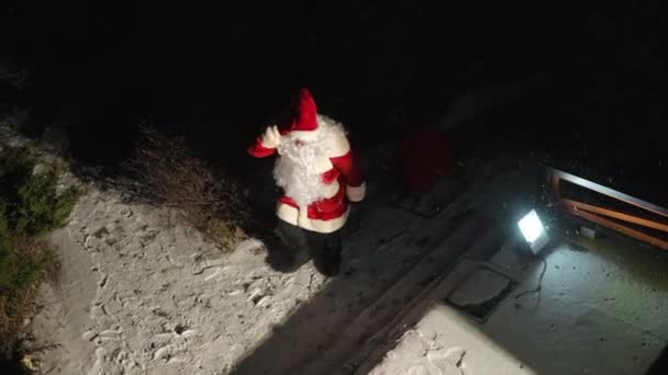 圣诞老人拉着雪橇从夜色中走出来 把红包和礼物放在雪地的门廊上 圣诞之夜 白人男子在户外的高角镜头 奇迹和惊奇 — 图库视频影像