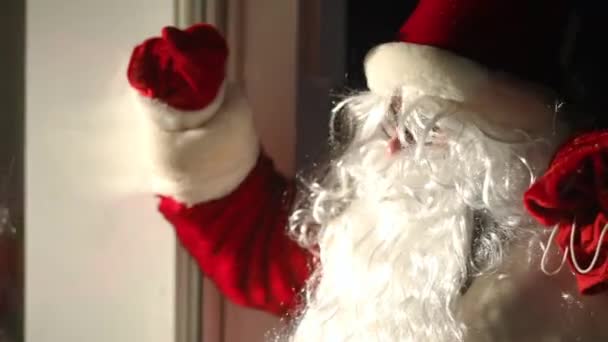 侧面看积极的圣诞老人在门外招手邀请 白胡子戴眼镜的白种人 夜晚黑暗中的礼品袋 — 图库视频影像