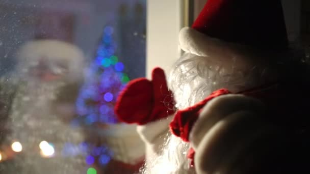 サンタの衣装を着たクローズアップ白人男性が窓のジェスチャーで屋外に招待します サイドビューポートレートの正男作る驚き上の雪のクリスマスの夜 — ストック動画