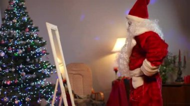 Beyaz adamın, Noel Baba kostümü denerken, oturma odasında aynanın önünde dikilirken çekilmiş bir portresi. Kendine güveni tam bir adam Noel sürprizi hazırlıyor.