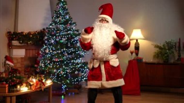 Oturma odasında Noel ağacı dönerken dans eden neşeli Noel Baba 'nın portresi. Yeni yıl arifesinde Kafkasyalı genç adam evde poz verirken eğleniyor. Heyecan ve kutlama konsepti