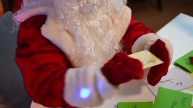 Çok renkli harflerle dolu yüksek açı masası ve tanınmayan Noel Baba dilekleri. Yeni yıl arifesinde kırmızı kostümlü bir adam. Noel mucizeleri konsepti