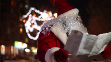 Kafası karışmış Noel Baba kağıt harita ile dışarıda duruyor ve yön arıyor. Noel arifesinde, gece şehrinde kırmızı kostümlü kayıp beyaz adamın portresi. Yeni yıl konsepti