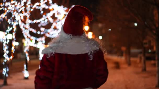 Noel Baba Nın Karlı Bir Sokakta Yürürken Noel Işıklarının Uzaklaştığını — Stok video