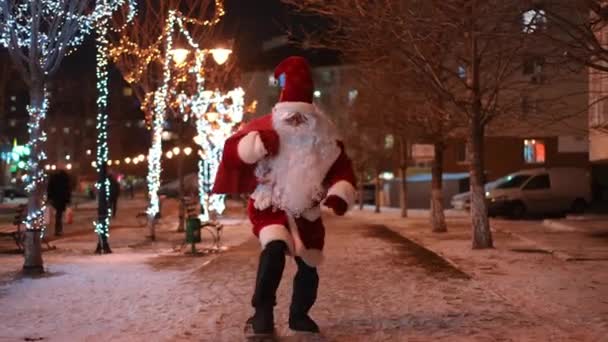 Joyful Santa Met Geschenken Zak Paardrijden Skateboard Besneeuwde Stad Straat — Stockvideo