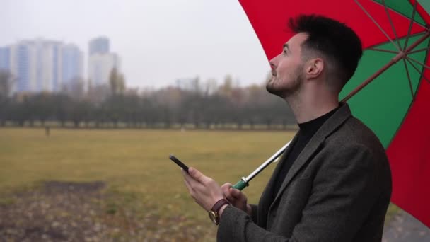 Joven Sonriente Satisfecho Con Teléfono Inteligente Parado Aire Libre Día — Vídeo de stock