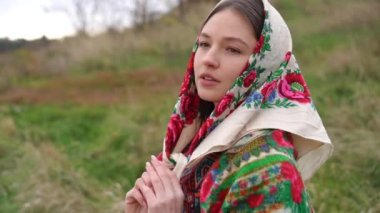 Genç ve güzel bir kadın ağır çekimde başörtüsü bağlıyor gözlerini kapıyor ağır çekimde gülümsüyor. İnce, muhteşem Ukraynalı bayanın portresi açık havada bulutlu bir sonbahar gününün tadını çıkarıyor. Yalnızlık ve yaşam tarzı