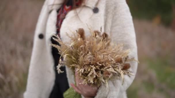 在户外用年轻女性的手捆着麦片 穿着传统乌克兰绣花衬衫的瘦弱女子站在秋天的田野上 戴着花束 爱国主义和自豪感概念 — 图库视频影像