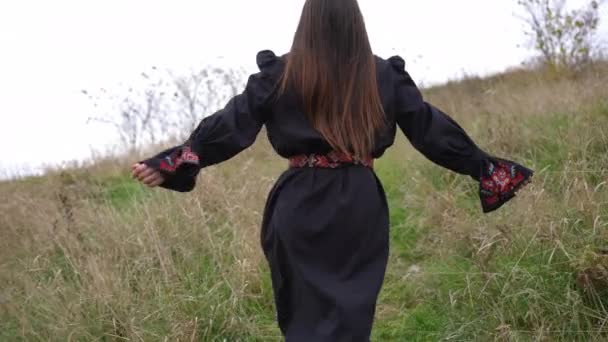 Отслеживающий Снимок Радостной Молодой Женщины Черном Платье Вышивкой Бегущей Холму — стоковое видео