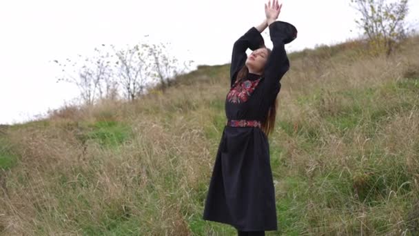 右屋外に立つスローモーションで手を上げ刺繍ドレスで魅力的な若いスリム女性を自信を持って 幸せなリラックスしたウクライナ人女性でナショナル服ともにライブカメラパンニングズームで — ストック動画