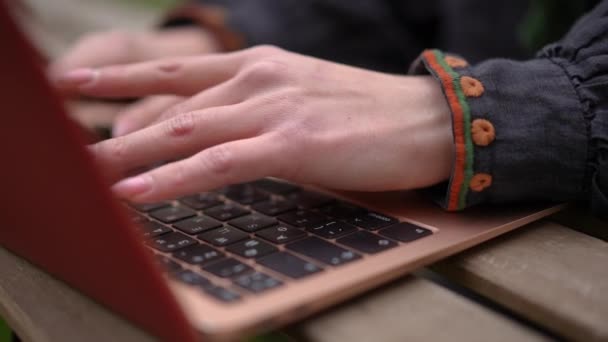 スローモーションでラップトップキーボードを入力する刺繍シャツのクローズアップ女性の手 伝統的な服のメッセージングオンラインで認識できない若いスリムウクライナ人女性が屋外に座って — ストック動画