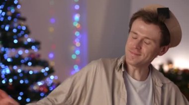 Kendine güvenen mutlu LGBT 'nin yakın plan portresi. Kapalı yerlerde dans eden, kadeh kaldıran, şampanya içen ve kameraya bakan adam. Evde Noel 'i kutlarken poz veren pozitif gülümseyen beyaz adam.