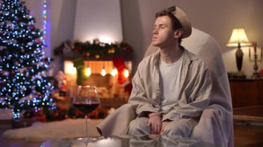 Depresyonda olan genç bir adam iç çekerek başını yana çeviriyor. Tatilde sallanan sandalyede oturuyor. Kafkasyalı LGBT elemanı, kırmızı şarap kadehine bakıp...