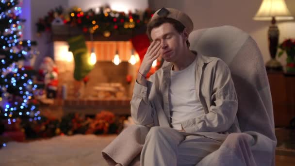 一个颓废的年轻人双手抱头 坐在右边摇椅上思考着 圣诞节前夕在家里描绘沮丧的白人男女同性恋 双性恋和变性者 孤独和假期 — 图库视频影像