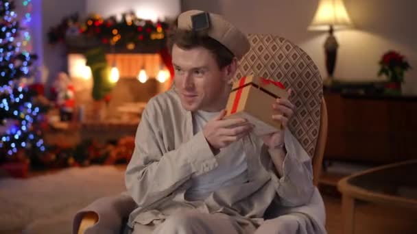 Smiling Caucasian Lgbt Guy Opening Christmas Gift Talking Sitting Rocking — Stock Video