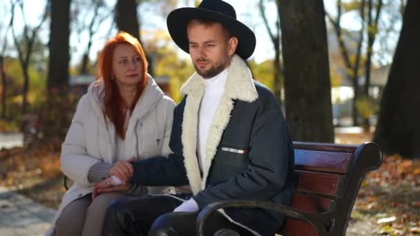 Przygnębiony Sfrustrowany Mężczyzna Siedzący Słońcu Ławce Jesiennym Parku Jako Kobieta — Wideo stockowe