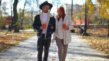 Ön manzara, beyaz bir erkek ve olgun bir kadının parkta kol kola yürüdüğünü gösteriyor. Dolly 'nin LGBT' li oğlu ve kızıl saçlı annesi sonbahar günü dışarıda sohbet ederken.