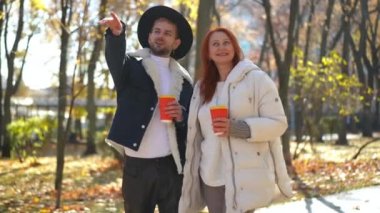 Neşeli zarif LGBT oğlu, Sunny Park sokağında dikilen olgun bir anneyle konuşurken kafasını çeviriyor. Mutlu beyaz erkek ve kadının portresi Sonbahar günü doğanın güzelliğine hayran olan sohbet eden