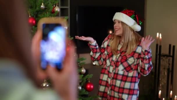 Весела Чарівна Тисячолітня Жінка Позує Різдвяному Дереві Вітальні Подруга Фотографує — стокове відео