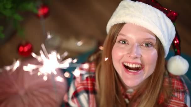 クローズアップトップビュークリスマスの輝きを手にカメラを見て微笑む喜びの美しい女性 満足のいく興奮白人女性の高い角度ビューの肖像画屋内で新年の前夜にポーズ — ストック動画