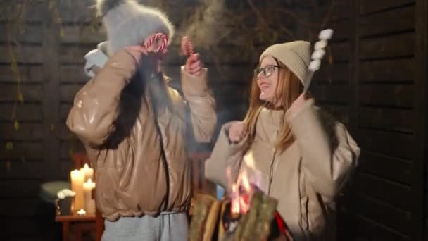 快乐无忧无虑的白人女人 带着油炸棉花糖和圣诞糖果 在户外篝火边慢动作舞动着 放松的朋友们 在除夕之夜欢欢喜喜 — 图库视频影像