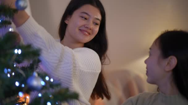 Charming Young Asian Woman Decorating Christmas Tree Talking Friend Laughing — Stock Video