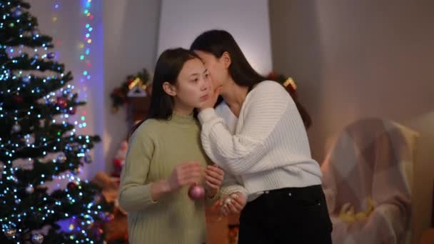 美丽的亚洲女人与朋友交谈时 低声耳语着微笑 圣诞前夜在室内分享流言的迷人朋友的画像 — 图库视频影像