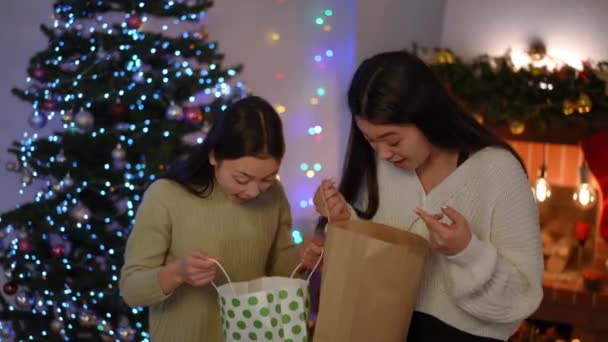 Två Förvånade Asiatiska Unga Kvinnor Tittar Inuti Kassar Med Presenter — Stockvideo